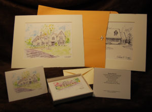 Matted watercolor house portraits with note cards in boxes.